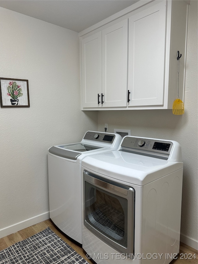 laundry room featuring cabinets, hardwood / wood-style floors, and washing machine and dryer