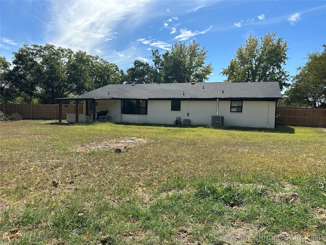 back of property featuring cooling unit and a lawn