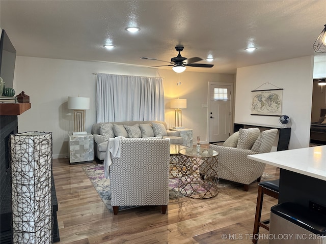 living room featuring a multi sided fireplace, hardwood / wood-style floors, a textured ceiling, and ceiling fan