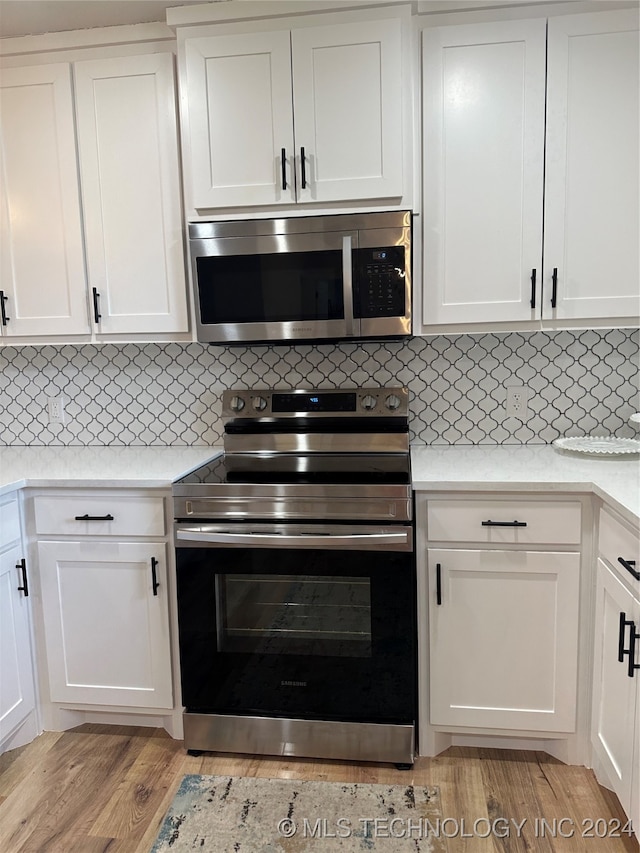 kitchen featuring tasteful backsplash, light hardwood / wood-style floors, appliances with stainless steel finishes, and white cabinetry