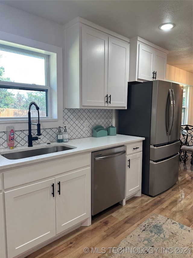 kitchen featuring appliances with stainless steel finishes, light wood-type flooring, sink, and white cabinets