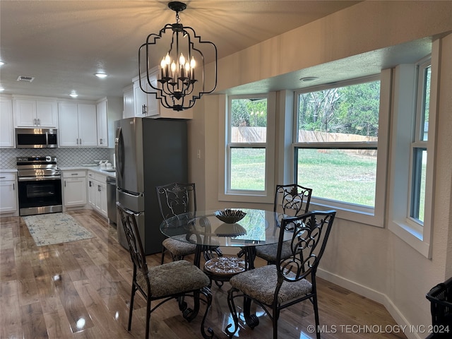 dining space with hardwood / wood-style floors and an inviting chandelier