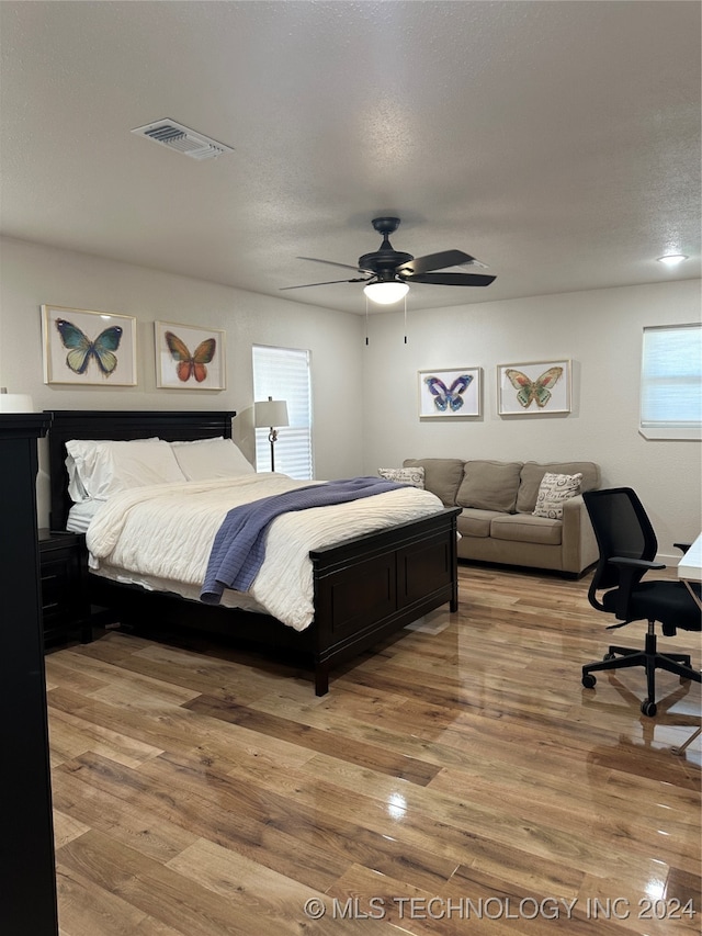 bedroom with ceiling fan, hardwood / wood-style flooring, and a textured ceiling