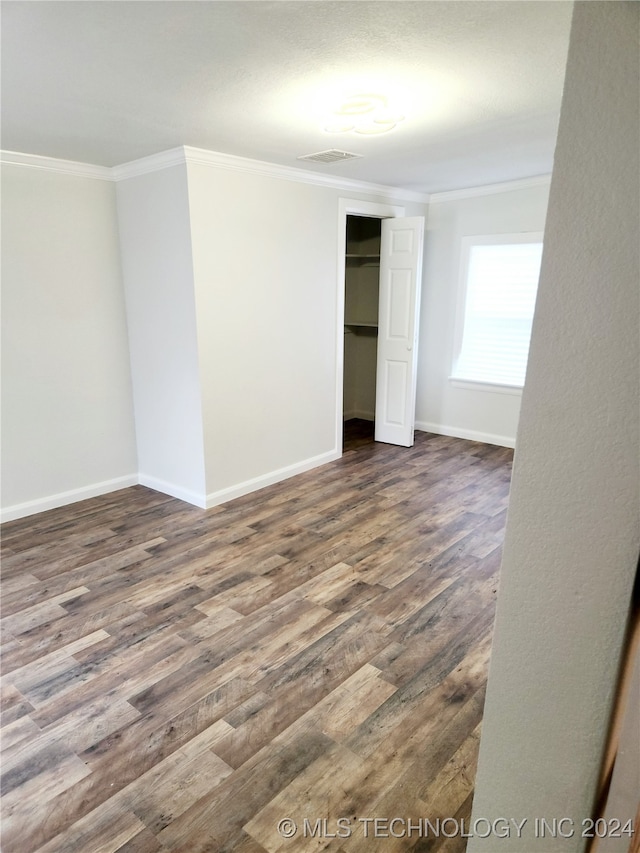 unfurnished bedroom featuring ornamental molding, a closet, and dark wood-type flooring