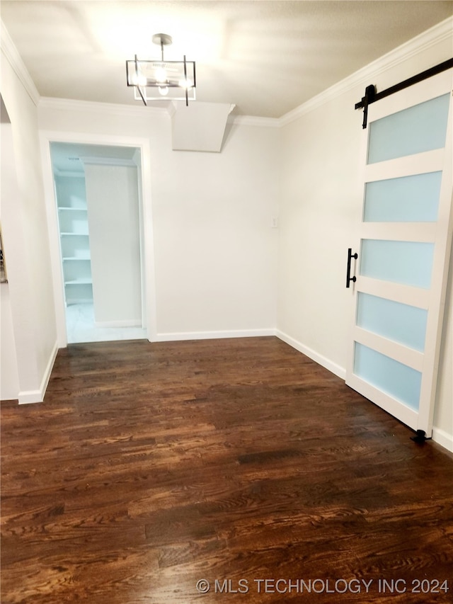 interior space with ornamental molding, a barn door, and dark hardwood / wood-style flooring