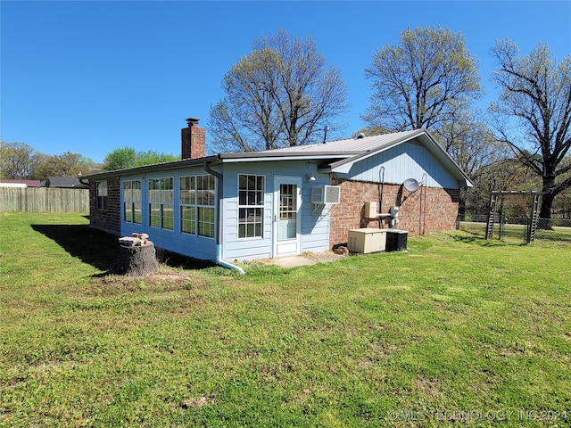 rear view of house with a wall unit AC, a yard, and central AC