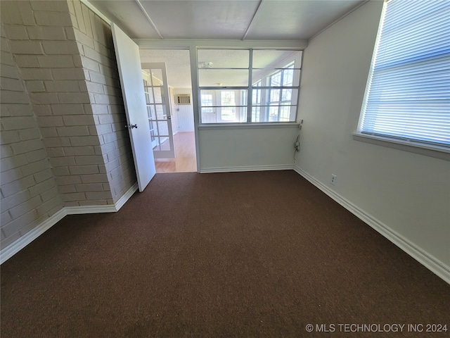 carpeted spare room with brick wall