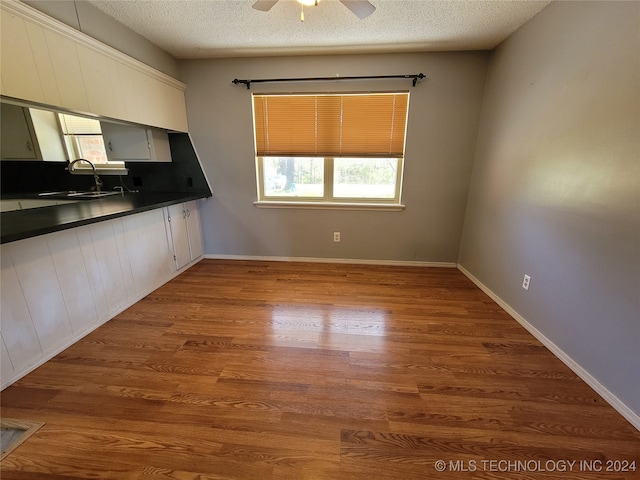 kitchen with ceiling fan, a textured ceiling, sink, and light hardwood / wood-style floors