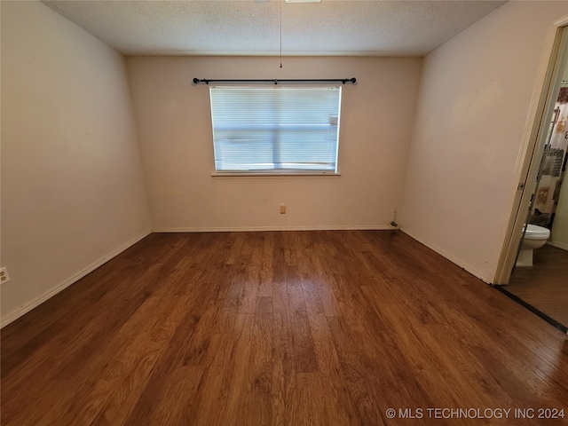 spare room featuring a textured ceiling and dark hardwood / wood-style floors