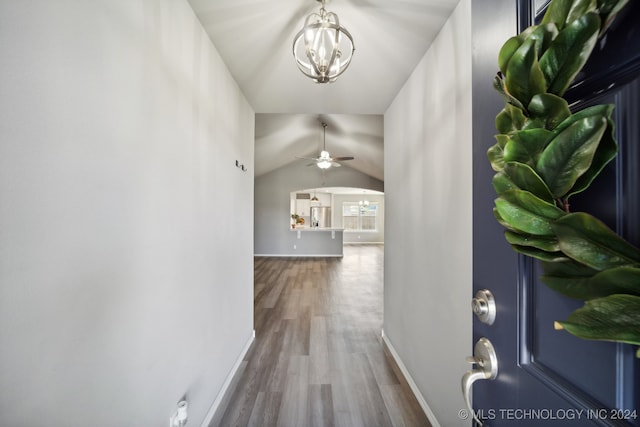 hall with hardwood / wood-style floors, an inviting chandelier, and lofted ceiling