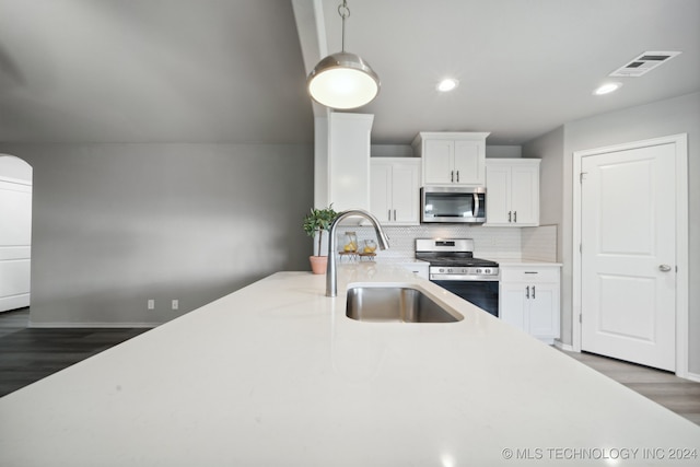 kitchen with decorative backsplash, white cabinetry, dark wood-type flooring, and appliances with stainless steel finishes