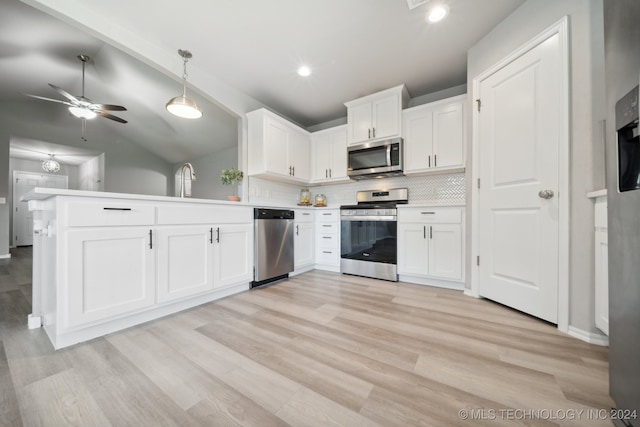 kitchen with lofted ceiling, white cabinets, hanging light fixtures, appliances with stainless steel finishes, and light hardwood / wood-style floors