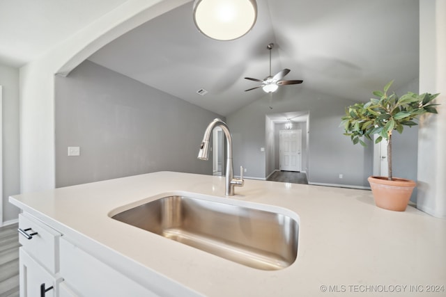 kitchen featuring white cabinets, sink, vaulted ceiling, ceiling fan, and wood-type flooring