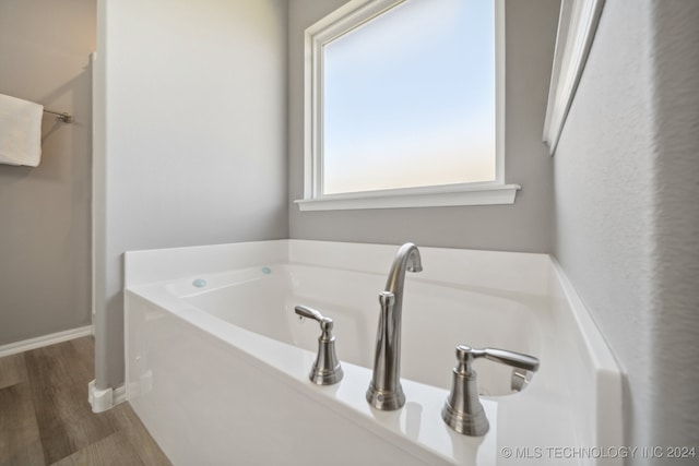 bathroom with hardwood / wood-style floors and a tub to relax in