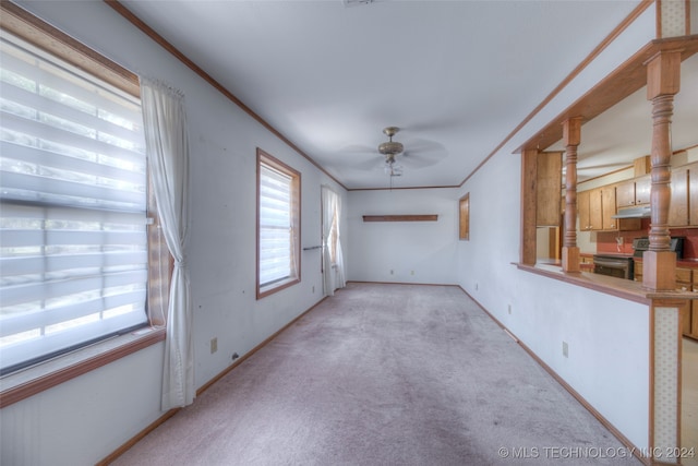 empty room featuring light carpet, ornamental molding, and ceiling fan