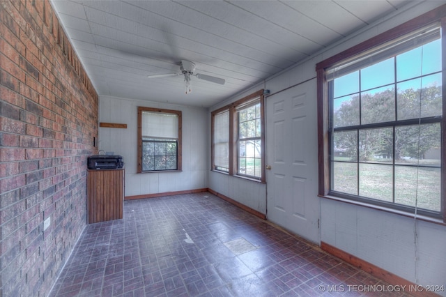 interior space featuring brick wall, ceiling fan, and plenty of natural light