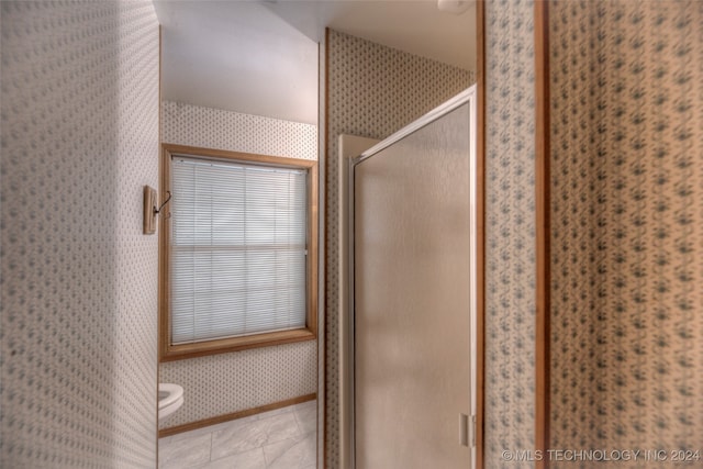 bathroom featuring tile patterned flooring, toilet, and walk in shower