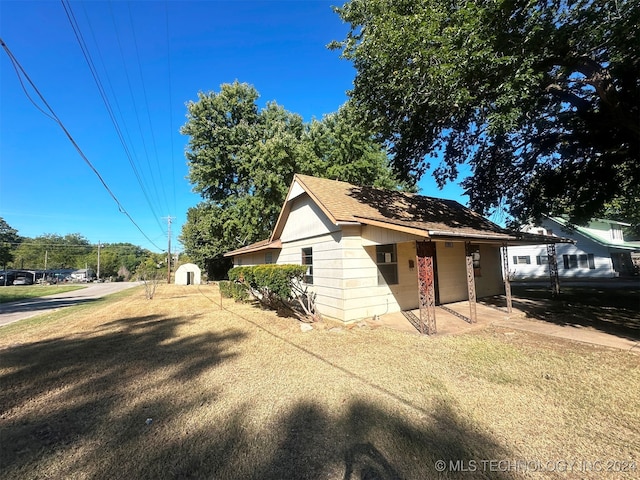 view of front of home with a storage shed and a front lawn