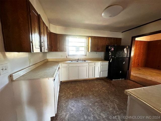 kitchen featuring sink, black fridge, and white cabinets