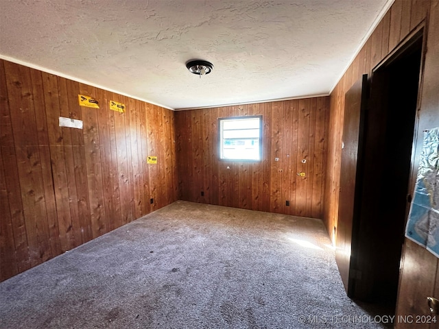 unfurnished room with ornamental molding, wooden walls, and carpet flooring