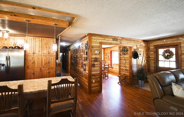 kitchen with a textured ceiling, dark hardwood / wood-style floors, decorative light fixtures, and stainless steel fridge