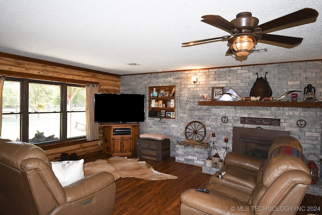 living room with wood-type flooring, a textured ceiling, a fireplace, ceiling fan, and brick wall