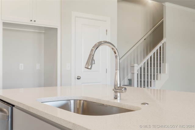 details with white cabinets, light stone counters, crown molding, and sink