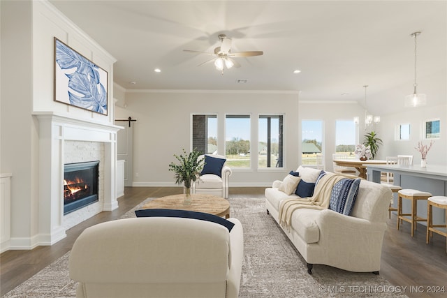 living room featuring a high end fireplace, ceiling fan with notable chandelier, crown molding, and dark wood-type flooring