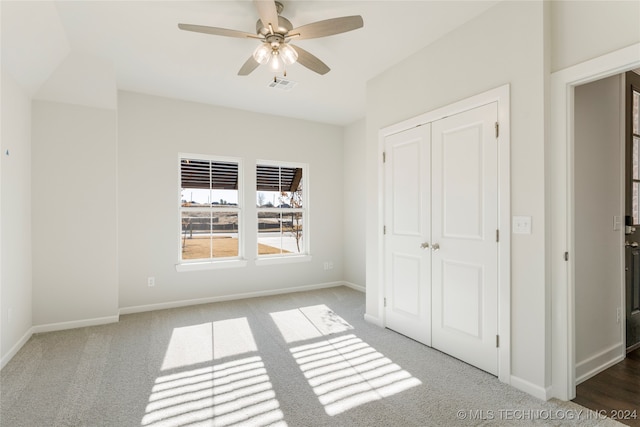 unfurnished bedroom with ceiling fan, carpet floors, and a closet