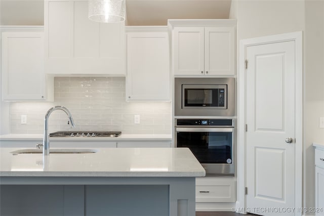 kitchen with decorative backsplash, white cabinetry, sink, and appliances with stainless steel finishes