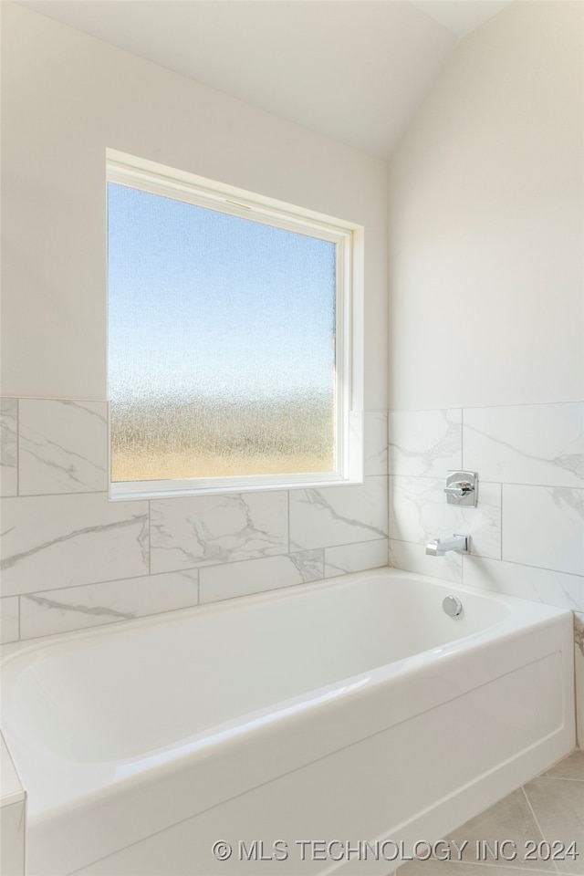 bathroom with a healthy amount of sunlight, a bath, and vaulted ceiling