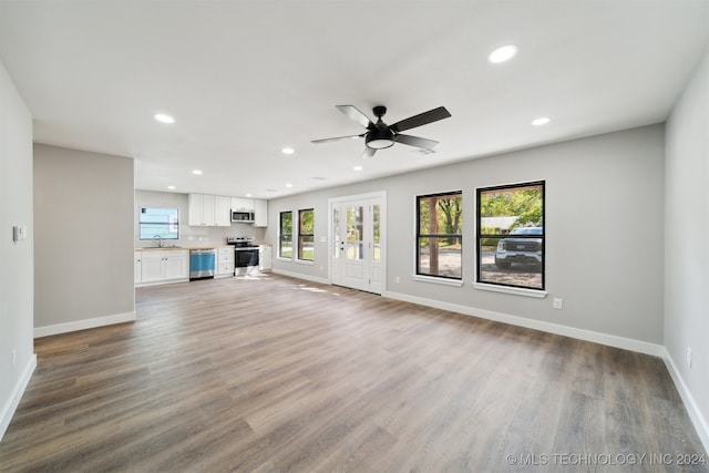 unfurnished living room featuring wood-type flooring, sink, and ceiling fan