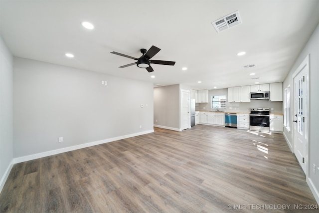 unfurnished living room featuring wood-type flooring, sink, and ceiling fan