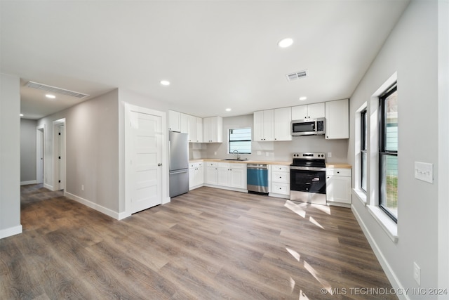 kitchen featuring white cabinetry, appliances with stainless steel finishes, and hardwood / wood-style flooring