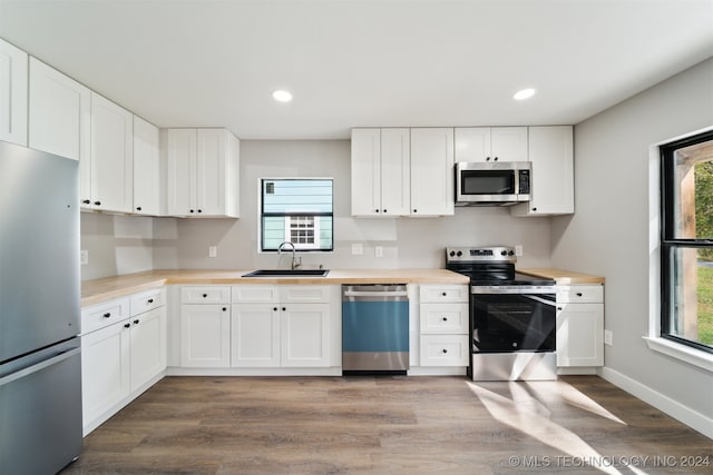 kitchen featuring white cabinetry, sink, stainless steel appliances, and a wealth of natural light