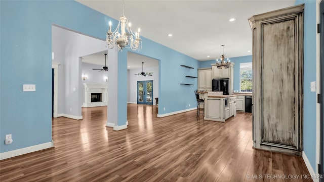 kitchen with hanging light fixtures, a kitchen island, black appliances, a breakfast bar area, and hardwood / wood-style floors