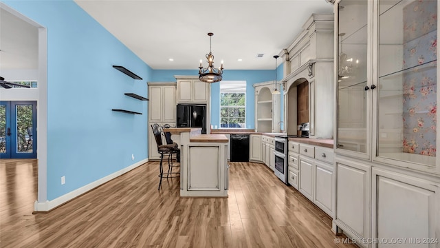 kitchen featuring pendant lighting, a kitchen island, light hardwood / wood-style flooring, black appliances, and a breakfast bar