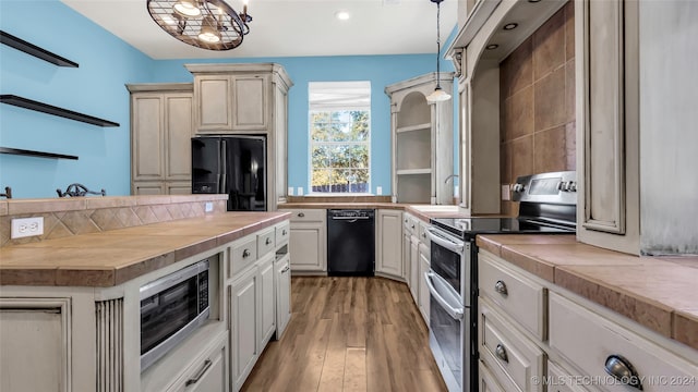 kitchen with a notable chandelier, butcher block counters, light hardwood / wood-style flooring, black appliances, and decorative light fixtures