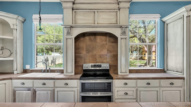 kitchen featuring hanging light fixtures, stainless steel range with electric stovetop, sink, and plenty of natural light