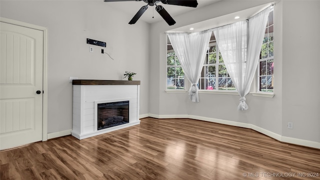 unfurnished living room with wood-type flooring, ceiling fan, and a wealth of natural light