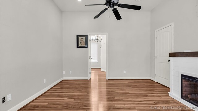 unfurnished living room with wood-type flooring and ceiling fan with notable chandelier