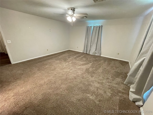 empty room with dark colored carpet and ceiling fan