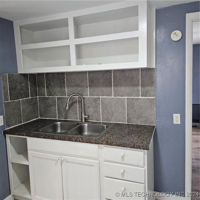 kitchen featuring wood-type flooring, backsplash, sink, and white cabinetry