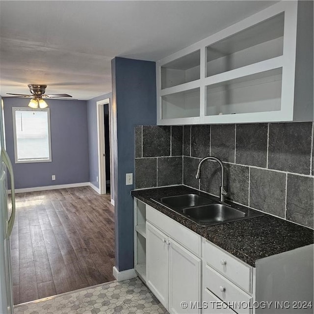 kitchen featuring white cabinetry, backsplash, light hardwood / wood-style flooring, ceiling fan, and sink