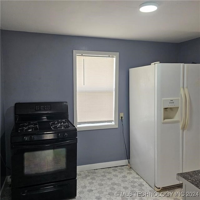 kitchen featuring black gas stove and white refrigerator with ice dispenser