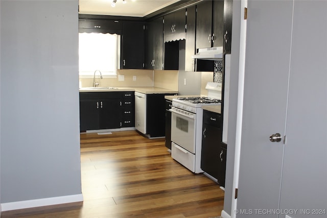 kitchen featuring decorative backsplash, sink, white gas range oven, and hardwood / wood-style flooring