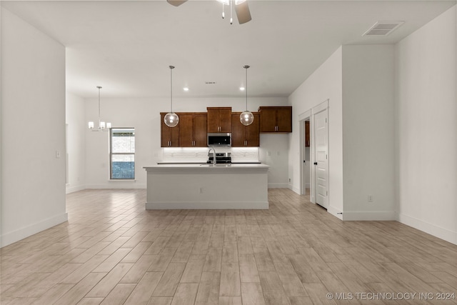 kitchen with an island with sink, sink, ceiling fan with notable chandelier, light hardwood / wood-style floors, and decorative light fixtures