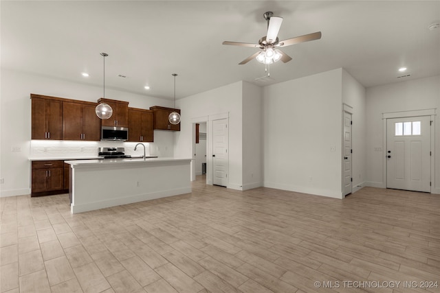 kitchen featuring sink, an island with sink, hanging light fixtures, light hardwood / wood-style floors, and stainless steel appliances