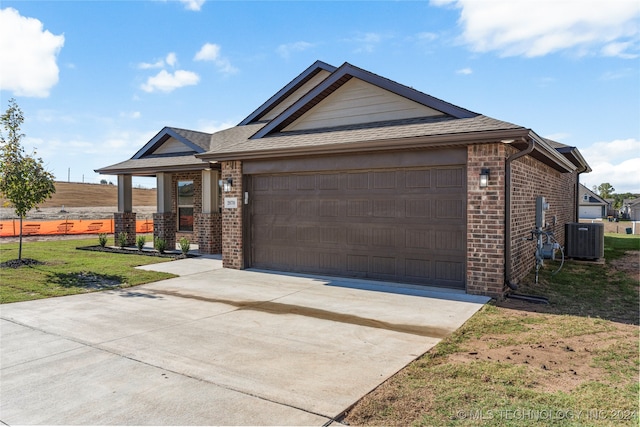 view of front of property featuring central AC, a front yard, and a garage