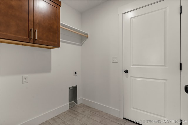 laundry room featuring light hardwood / wood-style flooring, electric dryer hookup, and cabinets